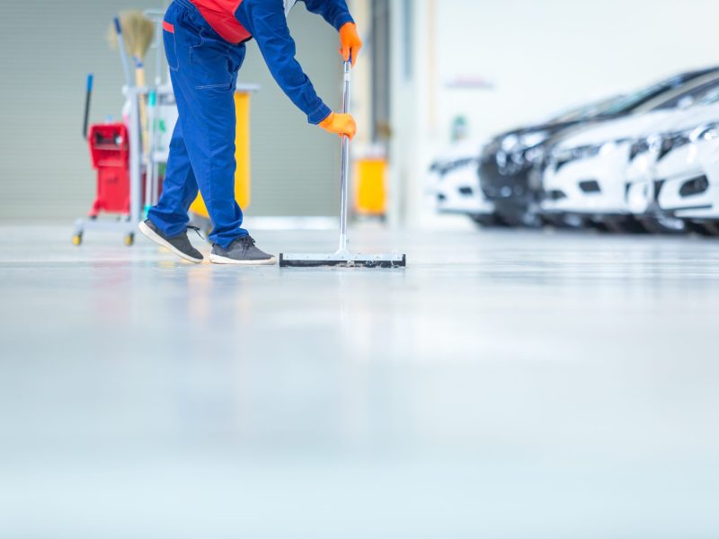 Car mechanic repair service center cleaning using mops to roll water from the epoxy floor. In the car repair service center.