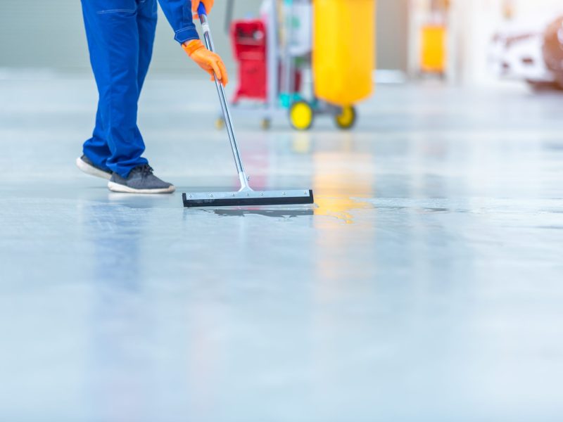 Car mechanic repair service center cleaning using mops to roll water from the epoxy floor. In the car repair service center.