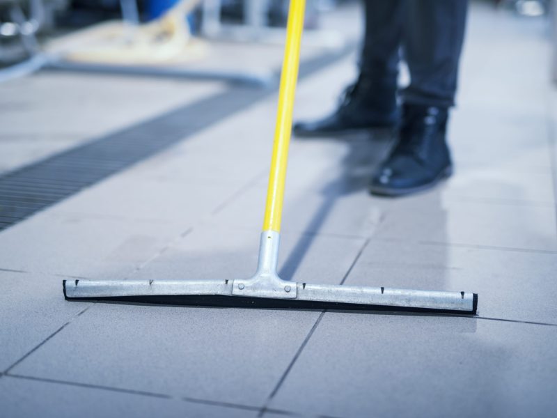 Close up of floor wiper mop cleaning industrial plant.