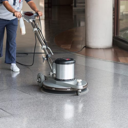 Woman worker cleaning the floor with polishing machine