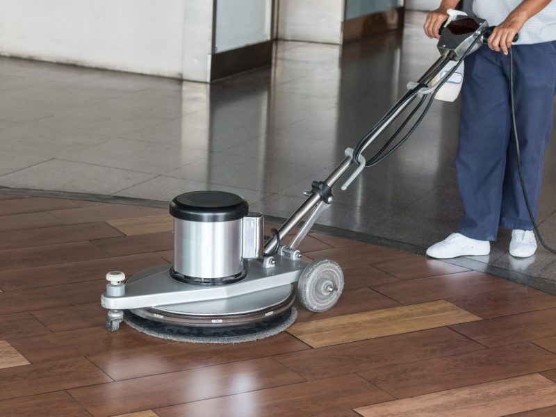 Woman worker cleaning the floor with polishing machine